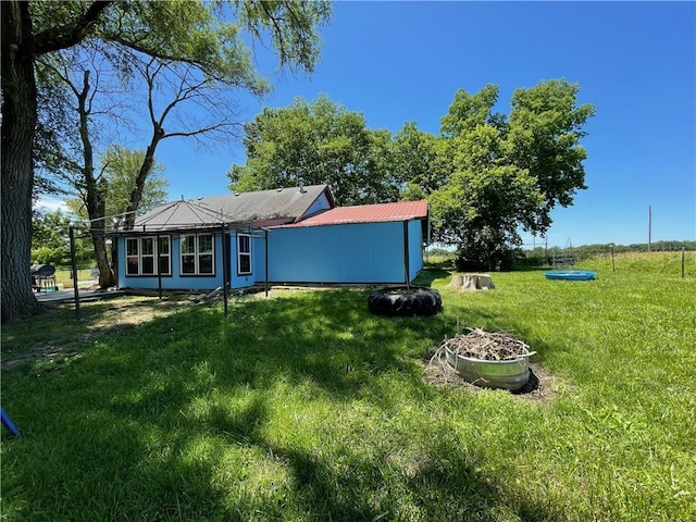 rear view of property featuring a yard and an outdoor fire pit