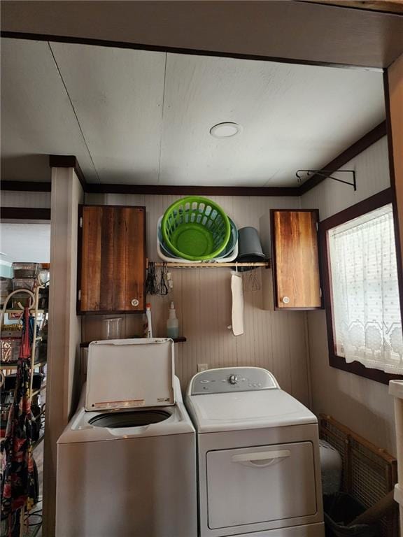 laundry area featuring cabinets, washing machine and dryer, and wood walls