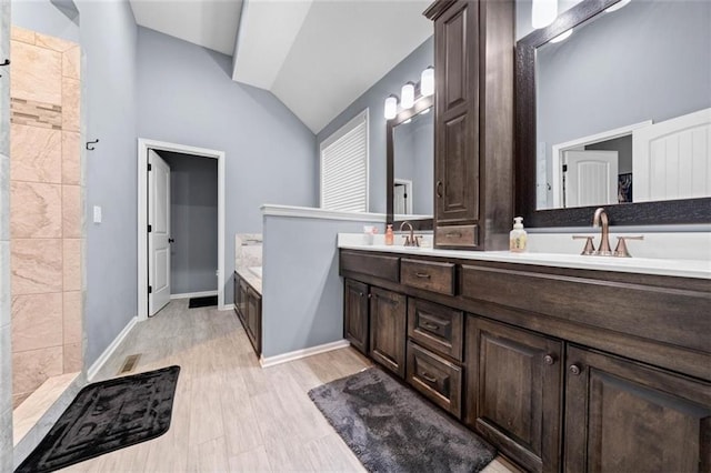 bathroom featuring lofted ceiling, vanity, a bathtub, and wood-type flooring