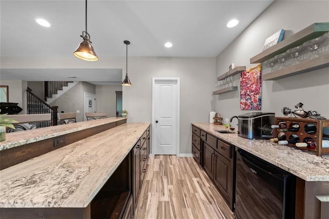 kitchen featuring pendant lighting, sink, dark brown cabinetry, light hardwood / wood-style floors, and light stone countertops