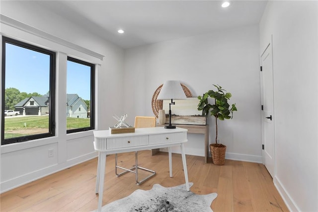 office with light hardwood / wood-style flooring and a healthy amount of sunlight