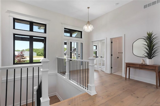 hallway with a chandelier, light wood-type flooring, and french doors