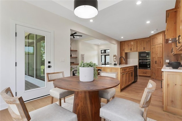 dining area with ceiling fan, light hardwood / wood-style floors, and sink