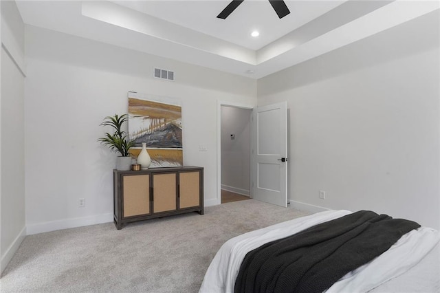 bedroom featuring ceiling fan, a raised ceiling, and light carpet