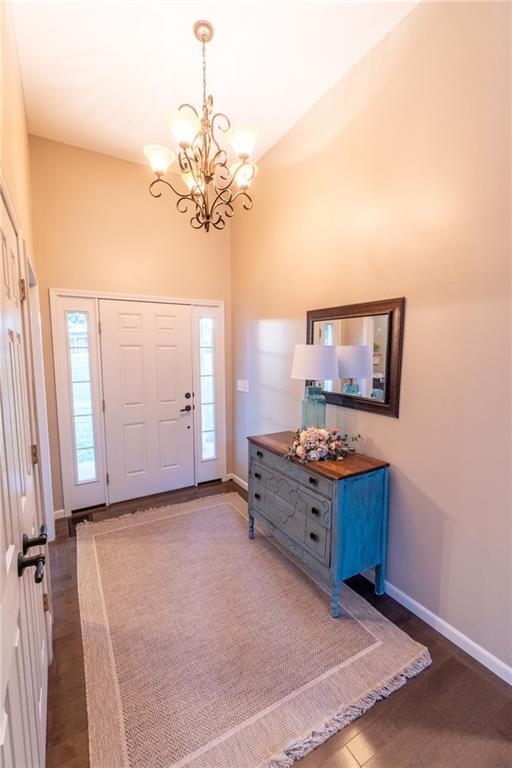 entryway featuring dark hardwood / wood-style floors, high vaulted ceiling, and a notable chandelier