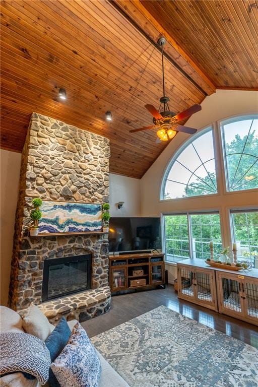 living room featuring wooden ceiling, a stone fireplace, beam ceiling, and ceiling fan