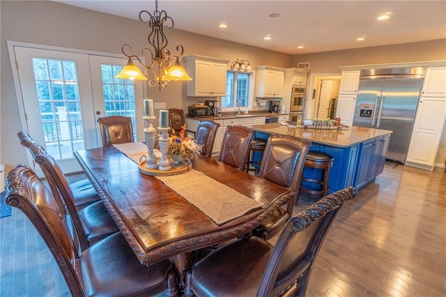 dining room featuring french doors, an inviting chandelier, light wood-type flooring, and sink