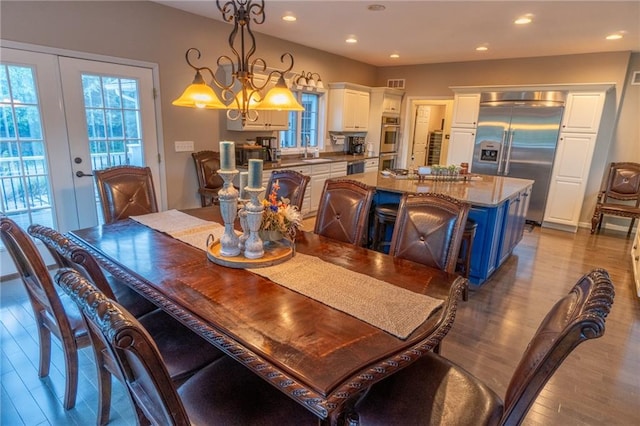 dining room featuring french doors, a notable chandelier, light wood-type flooring, and sink