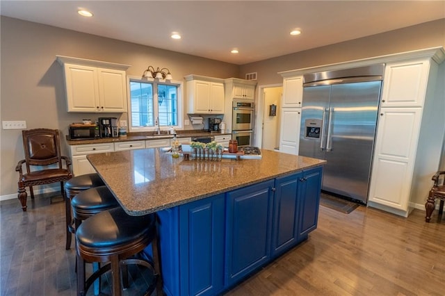 kitchen with a large island, stainless steel appliances, blue cabinets, and wood-type flooring