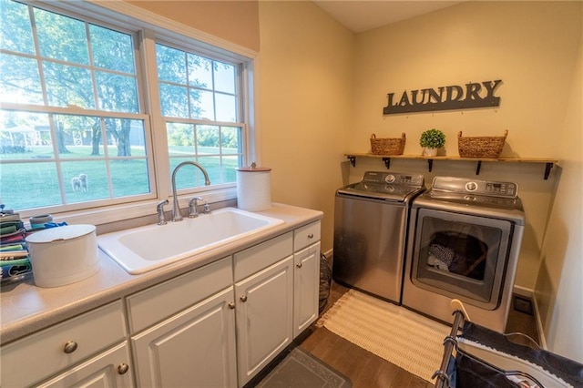 laundry room with cabinets, dark hardwood / wood-style floors, washer and dryer, and sink