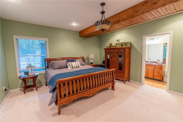 bedroom with beamed ceiling, light colored carpet, ensuite bathroom, and sink