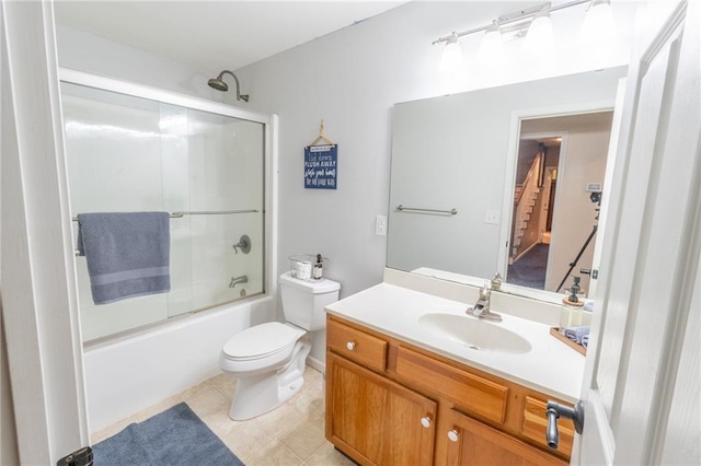 full bathroom with tile patterned floors, shower / bath combination with glass door, vanity, and toilet