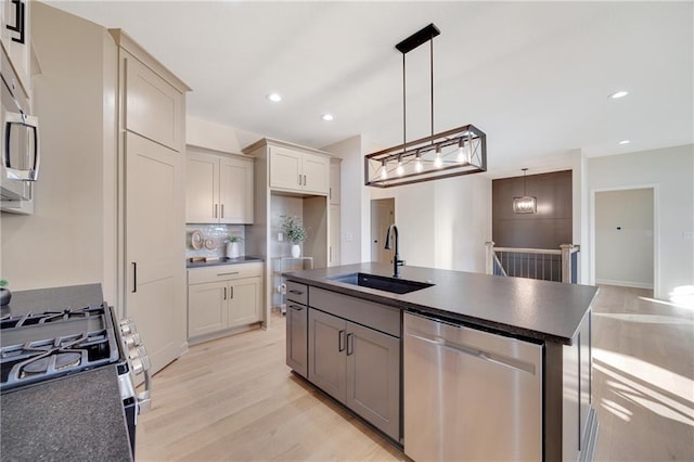 kitchen with sink, hanging light fixtures, backsplash, light hardwood / wood-style floors, and appliances with stainless steel finishes