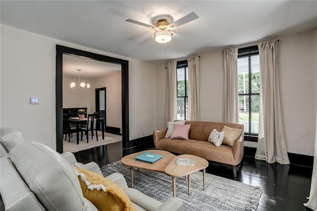 living room with ceiling fan with notable chandelier