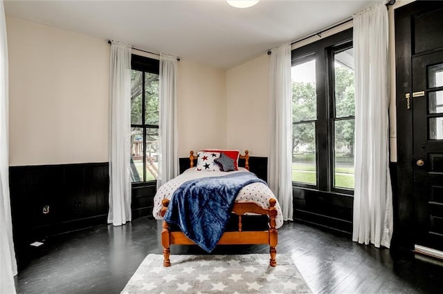 bedroom featuring multiple windows and dark hardwood / wood-style flooring