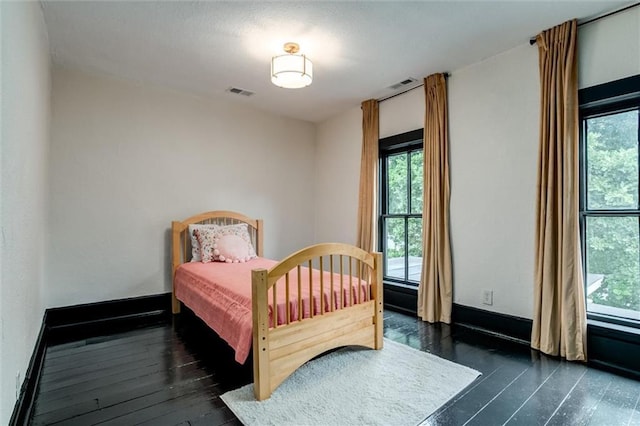 bedroom featuring dark hardwood / wood-style flooring and multiple windows