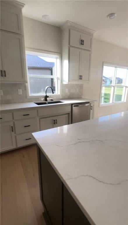 kitchen with sink, dishwasher, light stone counters, and tasteful backsplash