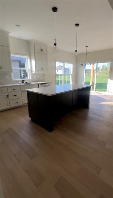 kitchen featuring white cabinetry, sink, a kitchen island, and decorative light fixtures