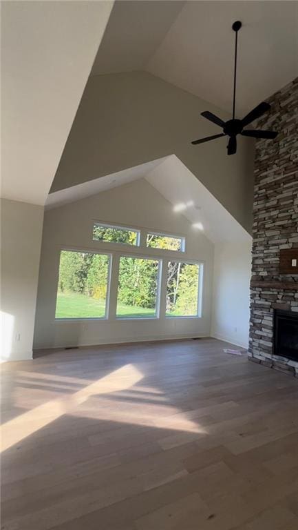 unfurnished living room featuring a fireplace, high vaulted ceiling, hardwood / wood-style flooring, and ceiling fan