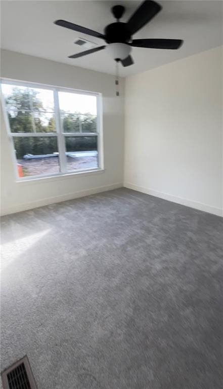 spare room featuring dark colored carpet and ceiling fan