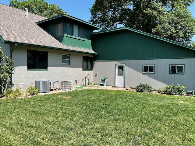 back of property with central AC and a yard