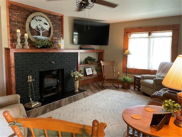 living room with brick wall, hardwood / wood-style floors, ceiling fan, and a fireplace