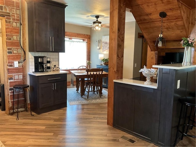 kitchen with decorative light fixtures, ceiling fan, light hardwood / wood-style floors, and tasteful backsplash