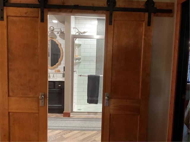 corridor featuring a barn door, sink, and wood-type flooring