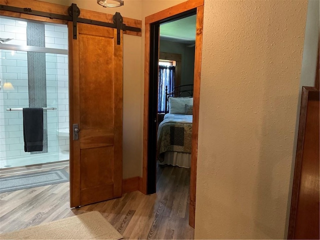 hallway with a barn door and wood-type flooring