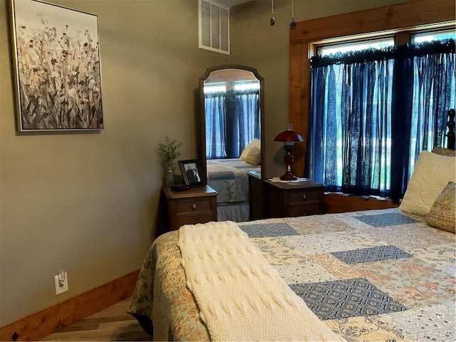 bedroom with wood-type flooring and multiple windows