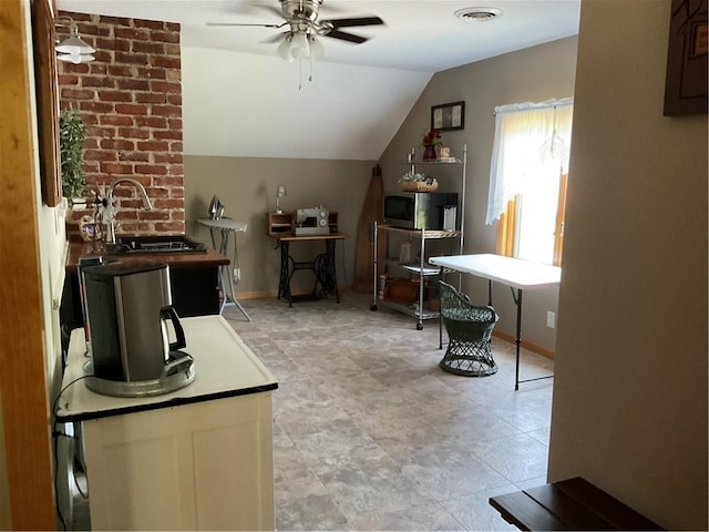 tiled office space with ceiling fan, lofted ceiling, sink, and brick wall