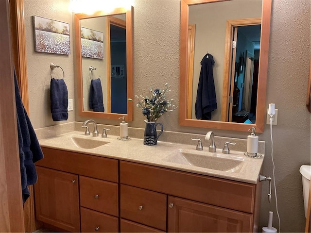 bathroom featuring dual sinks, toilet, and large vanity