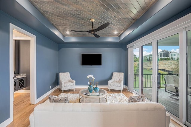 living room with a raised ceiling, ceiling fan, hardwood / wood-style floors, and wood ceiling