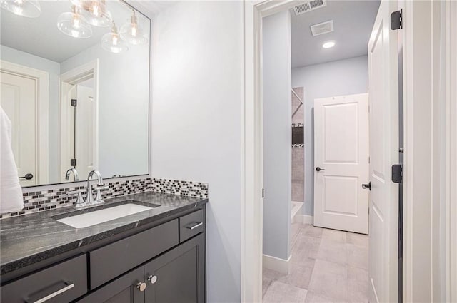 bathroom featuring tasteful backsplash, vanity, and tiled shower / bath combo