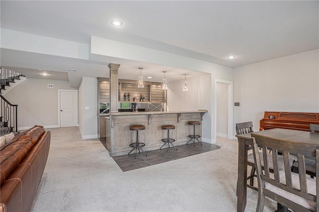 kitchen with a breakfast bar area, decorative light fixtures, kitchen peninsula, and light carpet