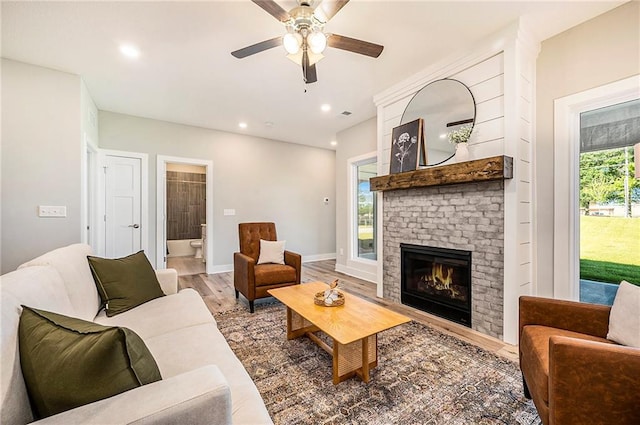 living room featuring ceiling fan, wood-type flooring, and a fireplace