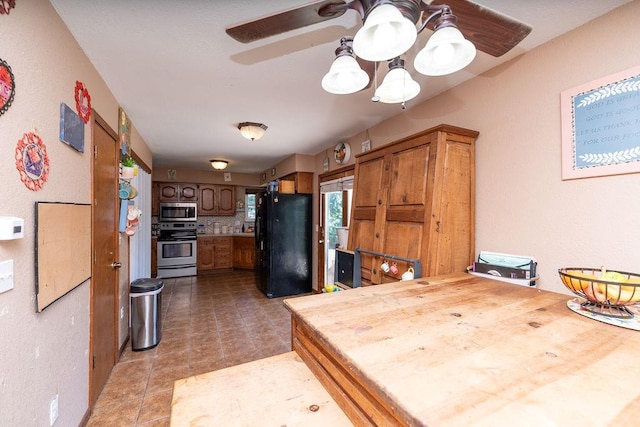 kitchen with stove, stainless steel microwave, tile patterned floors, ceiling fan, and black fridge