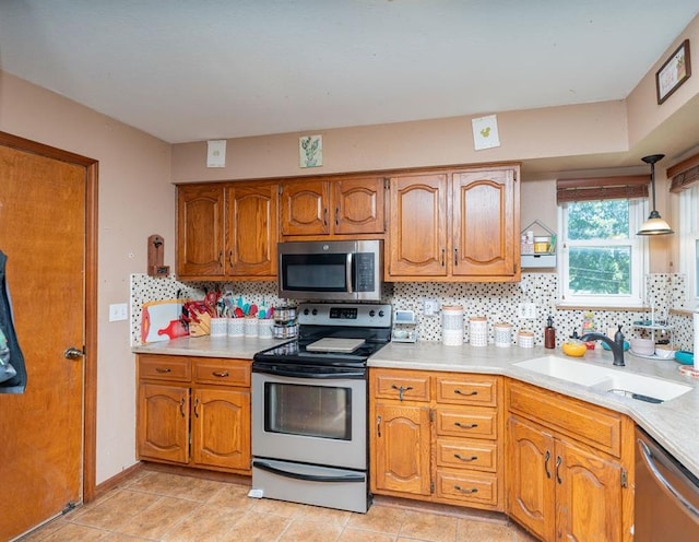 kitchen with hanging light fixtures, decorative backsplash, sink, appliances with stainless steel finishes, and light tile patterned floors