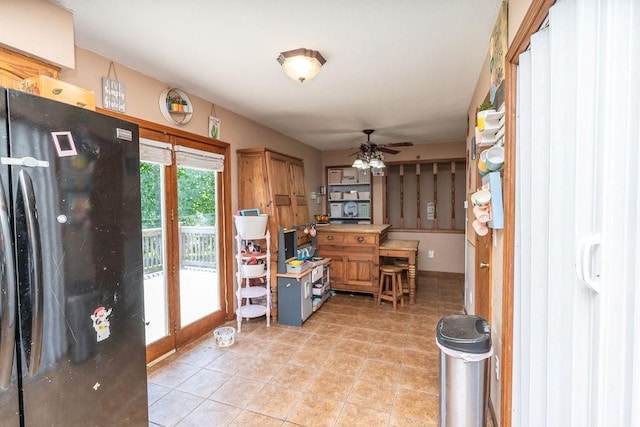 kitchen with black fridge, light tile patterned floors, and ceiling fan