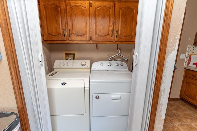 washroom featuring separate washer and dryer, cabinets, and light tile patterned floors