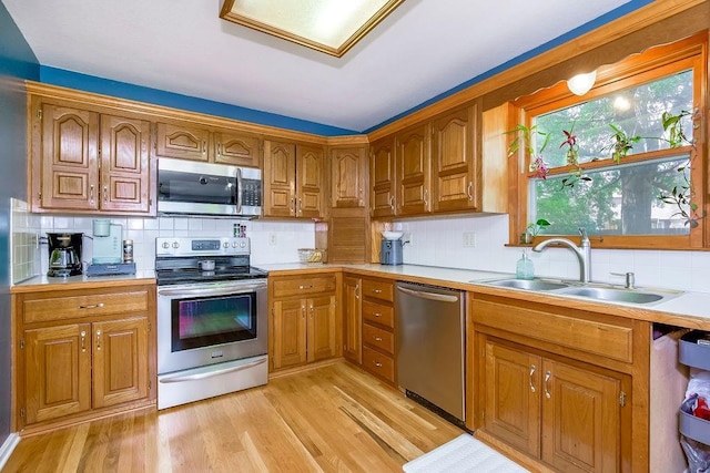 kitchen featuring tasteful backsplash, sink, stainless steel appliances, and light hardwood / wood-style floors