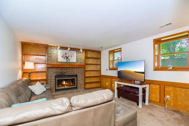 living room with a brick fireplace, light colored carpet, and built in features