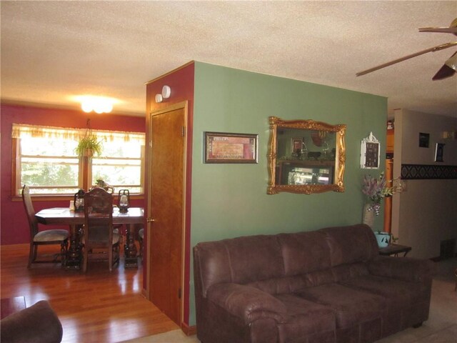 living room featuring a textured ceiling, wood-type flooring, and ceiling fan