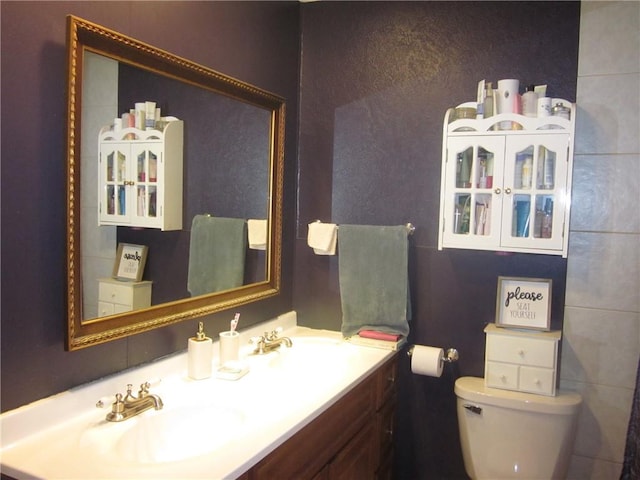 bathroom featuring oversized vanity, toilet, and tile walls