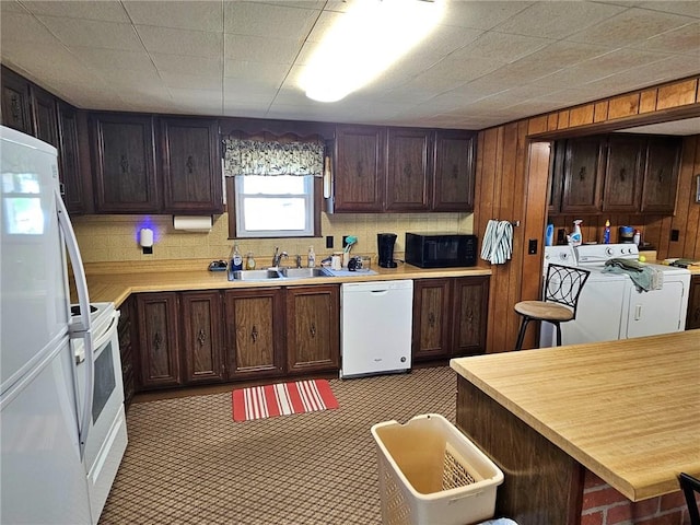 kitchen featuring dark brown cabinetry, tasteful backsplash, washing machine and dryer, sink, and white appliances