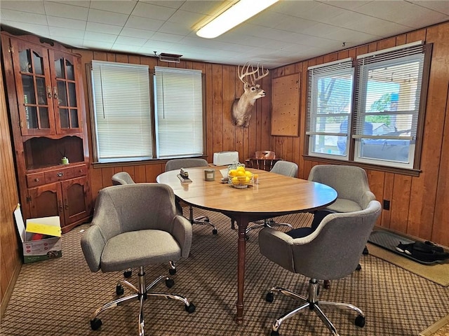 carpeted dining area with wood walls