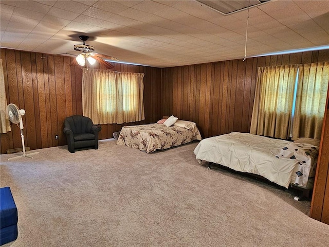 bedroom with carpet flooring, wooden walls, and ceiling fan