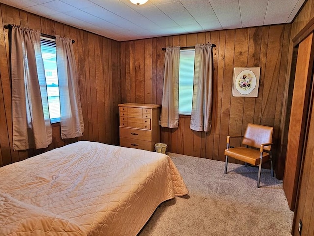 bedroom with carpet floors, multiple windows, and wood walls