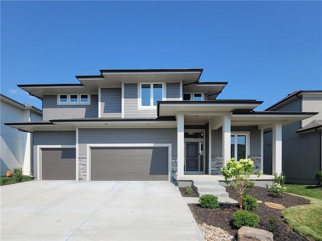 prairie-style home featuring a garage, stone siding, concrete driveway, and stucco siding