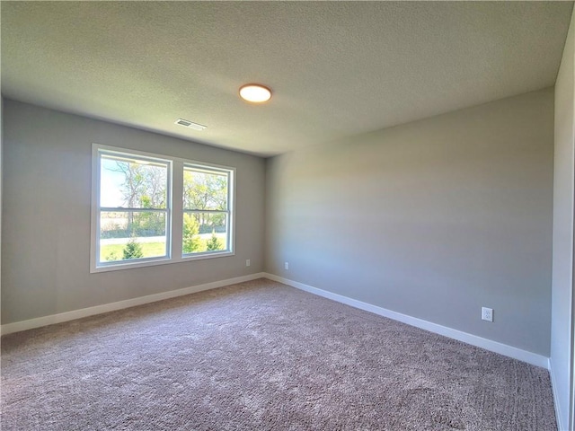 empty room featuring visible vents, a textured ceiling, carpet floors, and baseboards